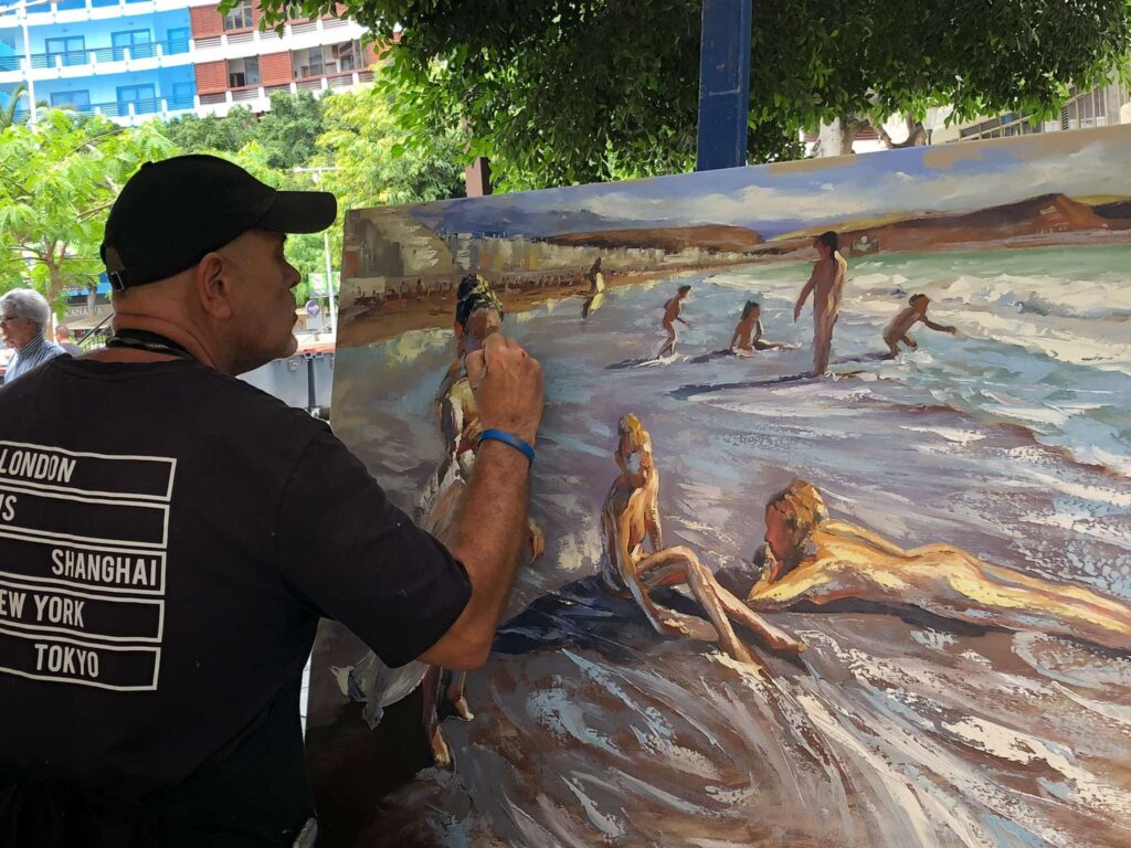 Paco Navarro pintando un cuadro con una espátula sobre una playa